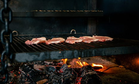 Viandes en train de griller au feu de bois dans la cheminée du restaurant Les Gaillards. à Vannes.